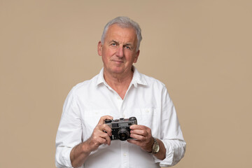 Handsome older photographer with old retro camera on brown background.