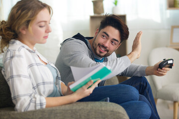 man playing video games and woman reading book