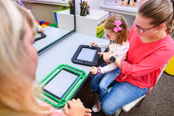Non-verbal girl living with cerebral palsy, learning to use digital tablet device to communicate....