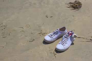 Fototapeta na wymiar zapatillas o tenisen la orilla del mar