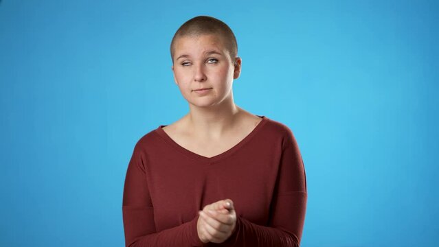 Young gender fluid non binary woman 20s look at camera claps without enthusiasm isolated on blue background studio portrait