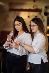 Two young girls using smart phone at the cafe