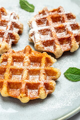 Sweet waffles sprinkled with powdered sugar prepared for serving. Delicious breakfast or snack. Restaurant menu, dieting, cookbook recipe top view