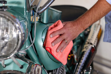 The man washing and cleaning motorbike. Man doing color polishing holds the soft microfiber cloth...