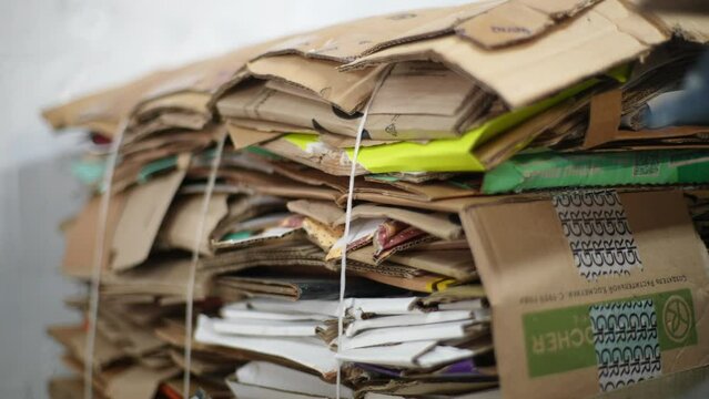 Close-up tracking shot of sorted cardboard waste ready for reprocessing. Garbage from stacks of cardboard for recycling. Concept of environment protection and zero waste. Shooting in slow motion.