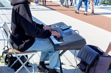 Street musician plays the synthesizer, someone's hand throws money