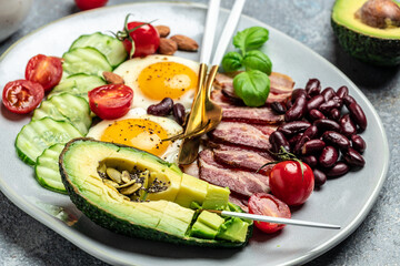 Keto breakfast with avocado, fried eggs, bacon, and beans. paleo keto breakfast diet lunch. Healthy nutritious paleo keto breakfast concept. Food recipe background. Close up