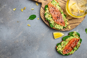 toast with avocadoo, salmon and spinach, nuts on a wooden board. Long banner format. top view