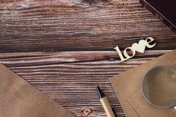 Love word written with wooden letters in heart shape, old-fashioned paper, magnifying glass, pen,...