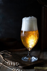 Glass of beer with a foamy cap on a wooden table