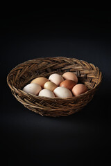 Chicken eggs in a basket on a black background