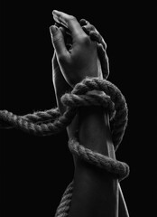 Hands of a man with hands tied with ropes. Photo black and white