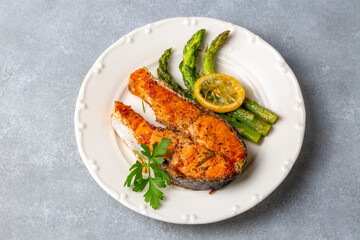 Grilled, baked salmon served on a plate with asparagus and potatoes