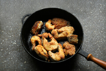 Top view of a frying pan with a fried pike river fish on a marble table