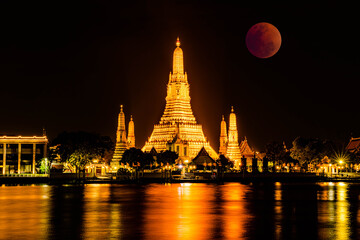Naklejka premium BANGKOK, THAILAND - November 8, 2022 : Lunar Eclipse, Super Red Full Moon taken from top side of “Wat Arun Temple”, This is a wonderful natural phenomenon with the view along Chao Praya River.