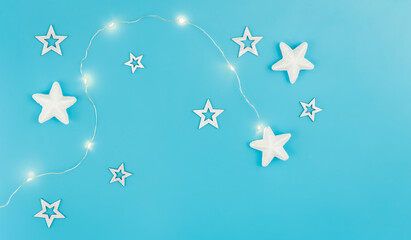 Blue Christmas background with garland and decorative stars, flat lay.
