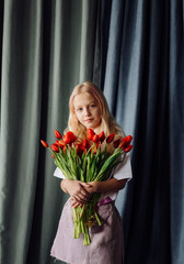 little girl with bunch of red tulips