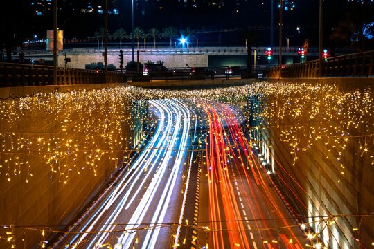 Modiin city's road with blue and red car lights and decorated with festive glowing garlands at night