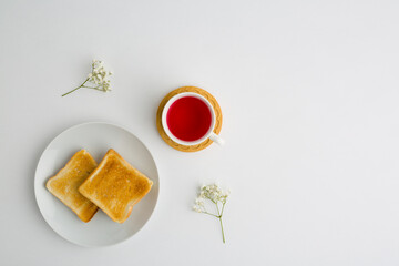 Cup of tea and toasted bread with small white flowers