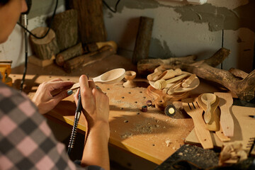 Female using power working tools graver for wooden utensils spoon