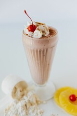 Vertical closeup shot of a  glass of Chocolate Protein Shake with Cherry against white background