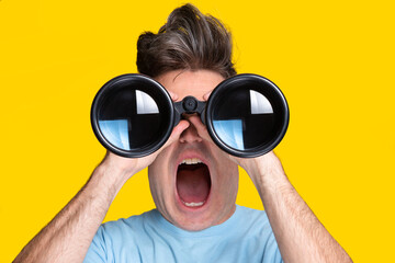 A man looking through binoculars with a surprised expression