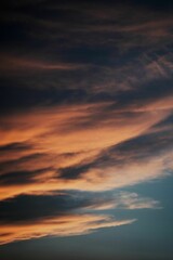 Fototapeta na wymiar Vertical shot of an orange cloudscape view in a dark sky at sunset