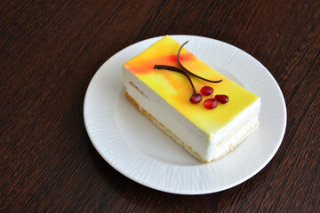 piece of citrus cake decorated with chocolate and pomegranate seeds on white saucer isolated