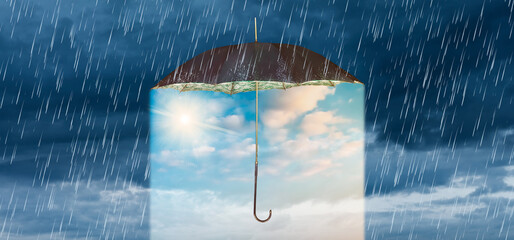 Concept of storm and heavy rain with a vintage umbrella revealing a blue sky with shining sun