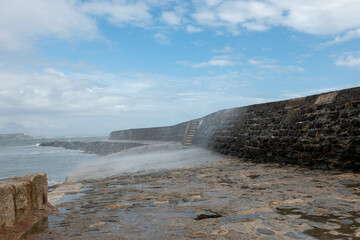 wave splashing over The World Famous Cobb at Lyme Regis Dorset England which features in Jane Austen's novel persuasion and the book and film The French Lieutenant's Woman by John Fowles