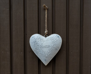 white heart with the inscription home hangs on a wooden brown background