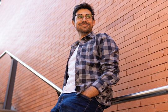 Cheerful man in checkered shirt standing on stairs