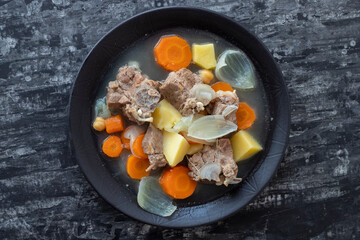 Boiled lamb meat with potatoes, carrots , onions, top view, copy space. Homemade winter comfort food.