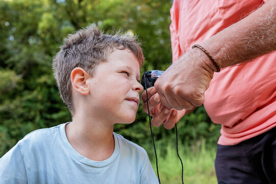 Crop man holding pocket monocular while kid looking at insect