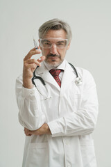 Portrait of Caucasian senior doctor wearing gown suit with stethoscope relax posing with medical needle while looking at camera.