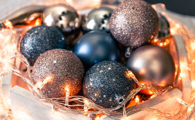 Close-up, shiny Christmas balls and a garland on a wooden stand.