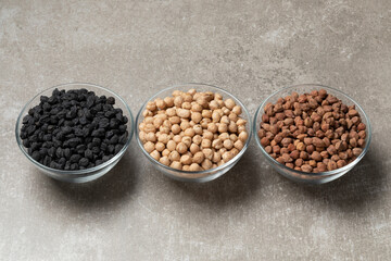 White medterranean garbanzo, black Italian ceci neri and brown indian Kala Chana chickpeas in a row on a stone background      