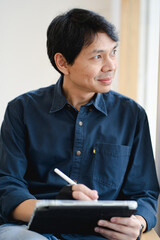 Naklejka premium asian freelancer man during creative and draw digital graphic by use tablet with happiness feeling