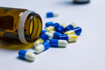 Medicine jar with spilled pills lying on a white surface - concept of pharmacies and health