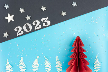 Obraz premium Christmas background with origami paper tree and number 2023, flat lay.
