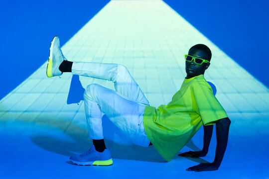 Stylish black man in trendy outfit dancing in studio