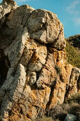 Closeup of a gray and yellow rocky cliff with cracks during the daytime