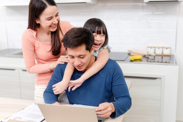 Work from home and concept family, beautiful Asian woman and Asian girl hugging her father's neck while working at home.