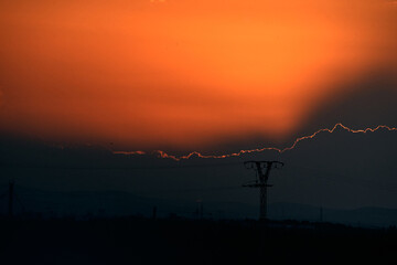 large high voltage tower at cloudy sunset with the sun hidden behind the clouds, albufera natural park valencia, spain