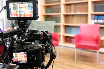 Two empty chairs in a TV studio with book panel in the background and camera in the foreground