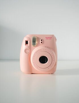 Vertical shot of a pink Instax mini 8 camera on a white background