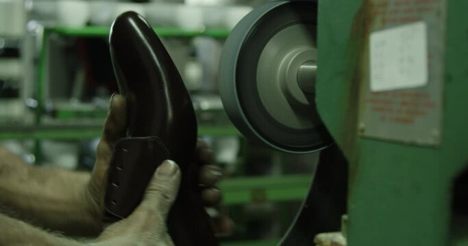 Shoemaker grinding a shoe at a shoe manufacturing plant, leather shoe being manufactured. Classic elegant shoe. 