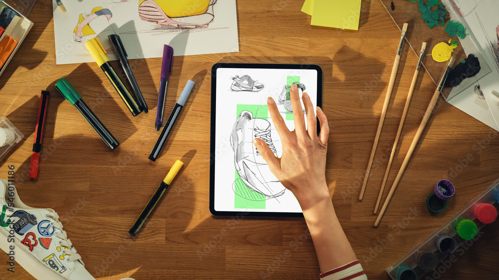 Aufkleber top view of female footwear designer drawing sketch of sneakers on tablet computer from upcoming col