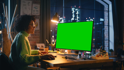 Fototapeta na wymiar Diverse Professional Freelancer Working on Personal Computer with Green Screen Chromakey on Display From Home. Black Woman Looking at Monitor, Browsing Through the Internet, Using Desktop PC.