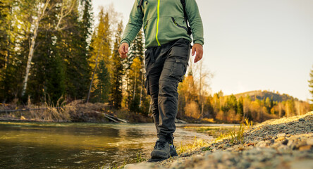 person walking on the beach of forest river in autumn 